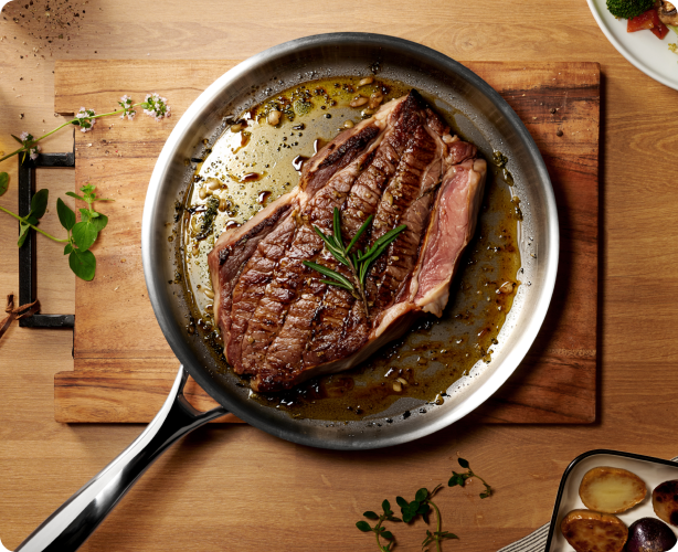 Steak cooking in a stainless frying pan