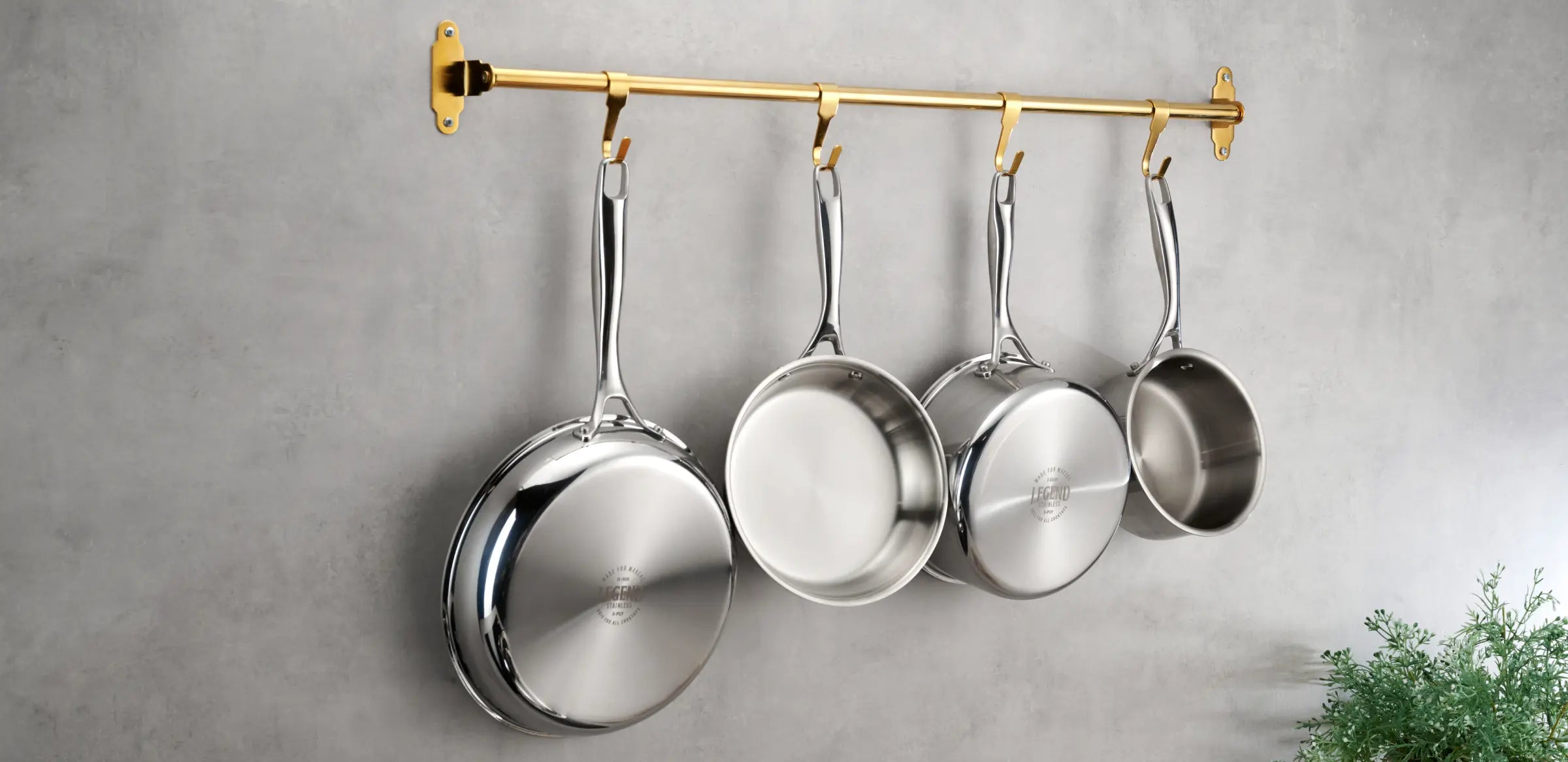 Legend 5-ply stainless pots and pans hanging on a brass rail